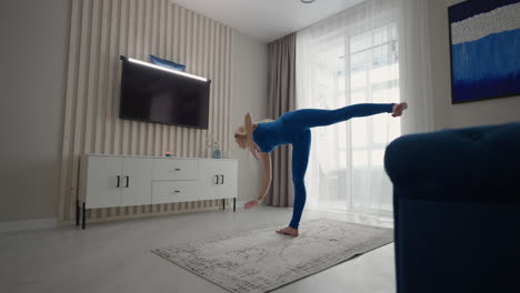 A-young-woman-in-isolation-does-yoga-at-home-on-a-mat-in-her-apartment